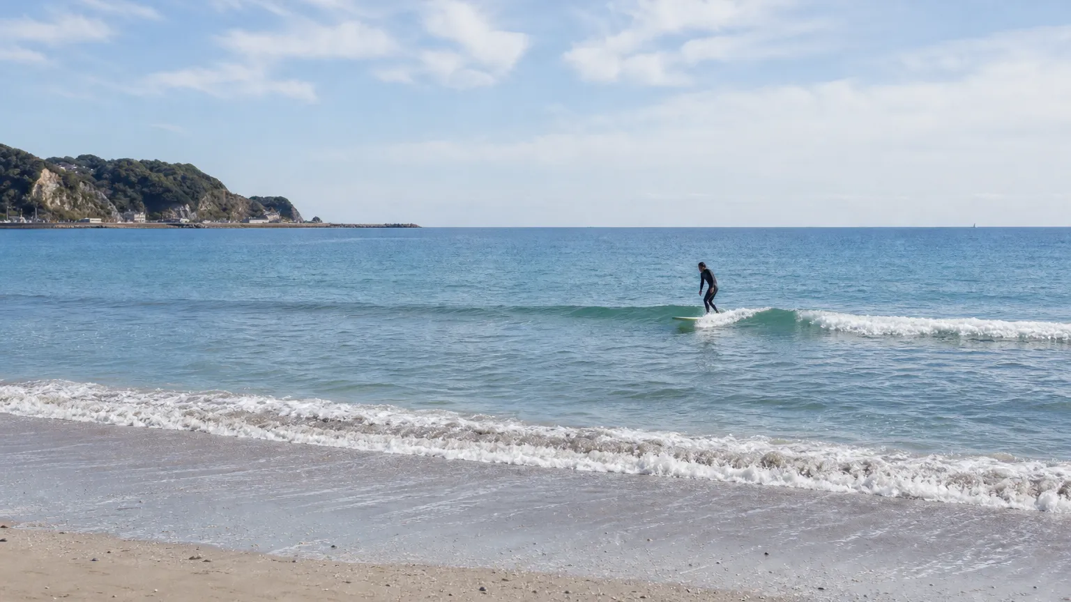 A surfer on a small wave, shot from the shore (photo goal)