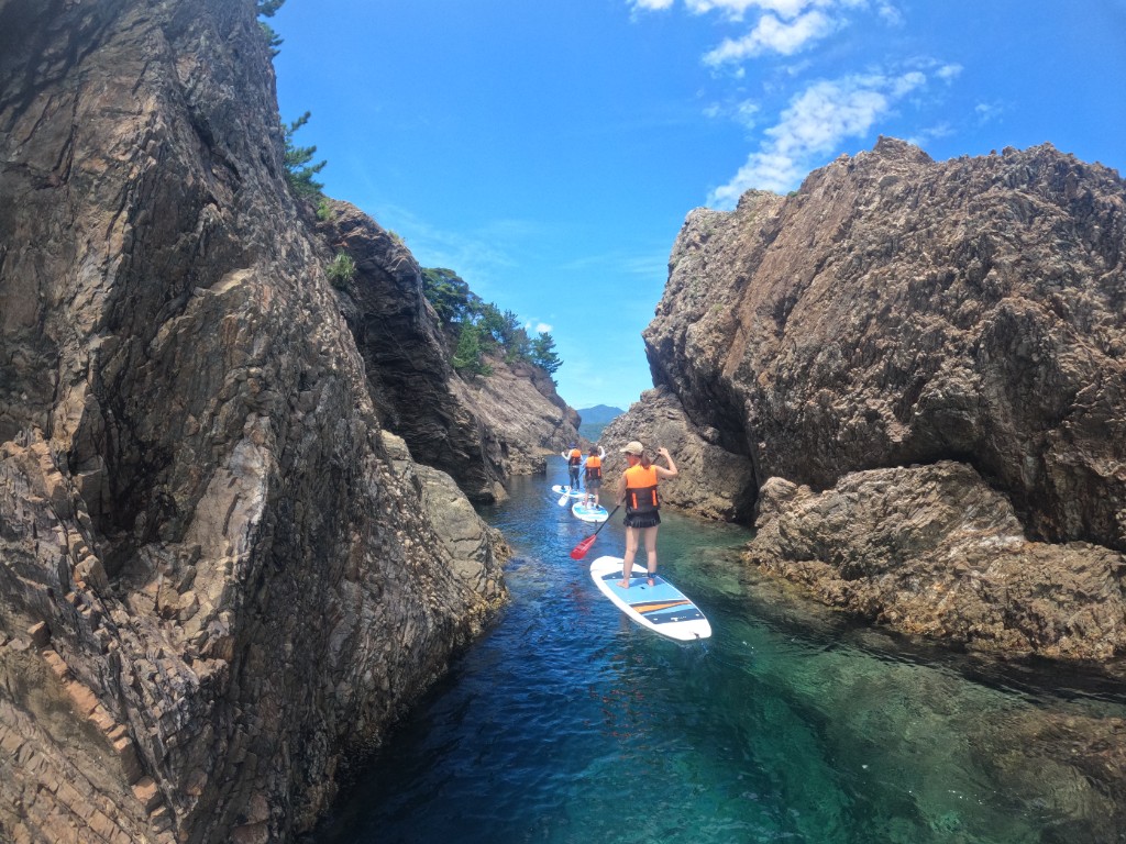 Paddling SUP toward a rock arch