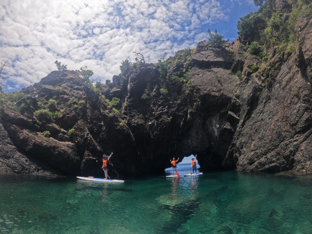 Two people paddling SUP in a green mountain bay