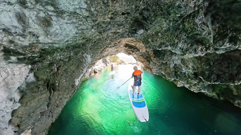 Paddling SUP under a rock arch