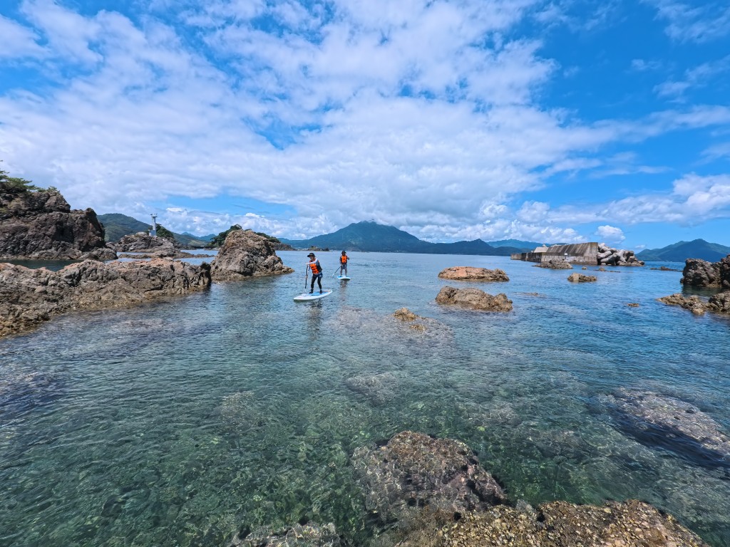 開けた浜をSUPで進むグループ