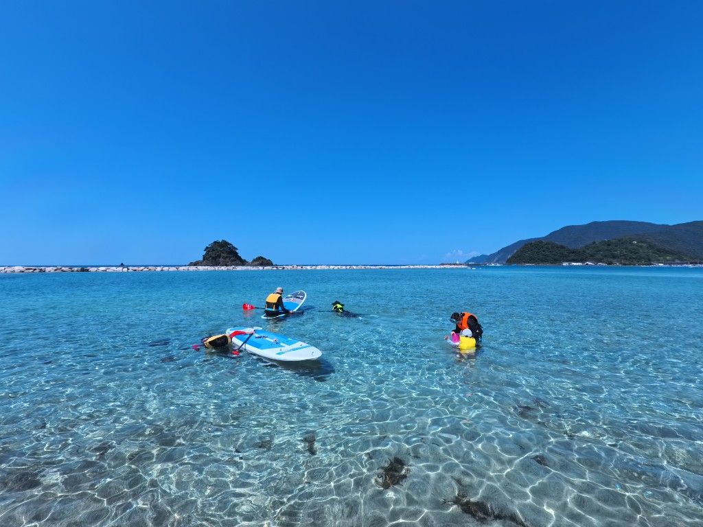 透明度の高い浅瀬をSUPで進むグループ